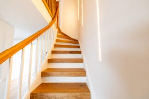 Elegante geschwungene Treppe mit warmer fugenloser Wandfläche und Holzgeländer, Basel – Malergenossenschaft Basel